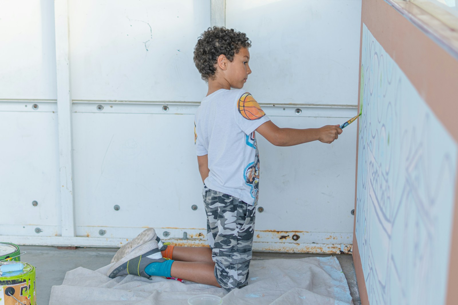 A boy paints on a wall.